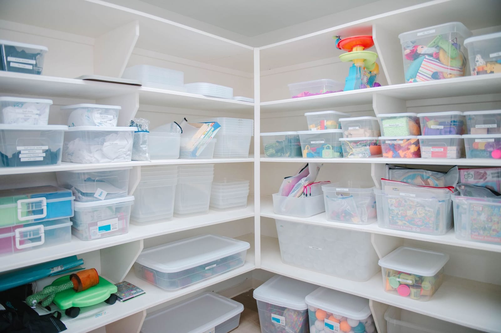 A pantry filled with lots of plastic bins and shelves.