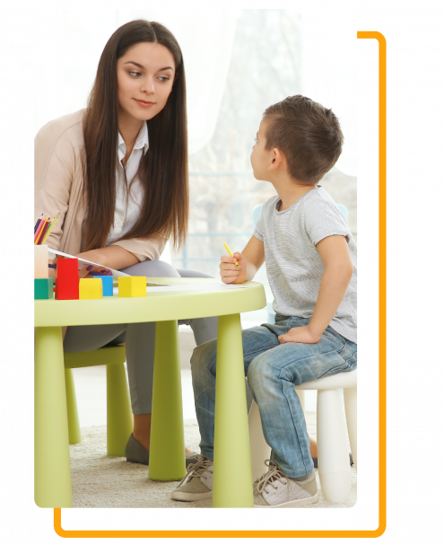 A woman sitting at a table talking to a young boy