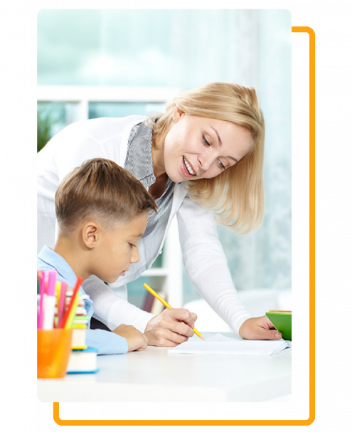 Woman assisting a child with writing at a desk, smiling.
