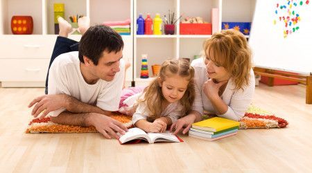 A family laying on the floor reading a book together